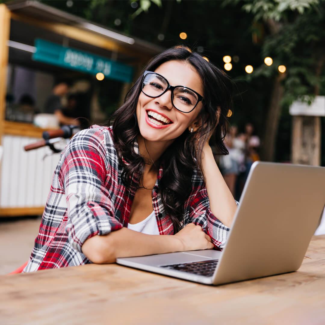 Woman smiling while comparing health plans on her laptop