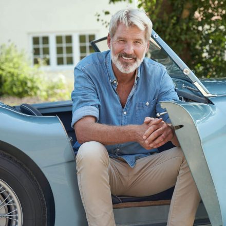 Retired man relaxing by his car