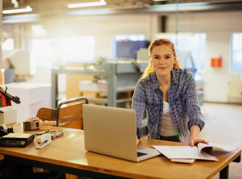 Young caucasian woman working with a laptop in a printing office