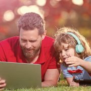Father and son lying on the grass with a laptop