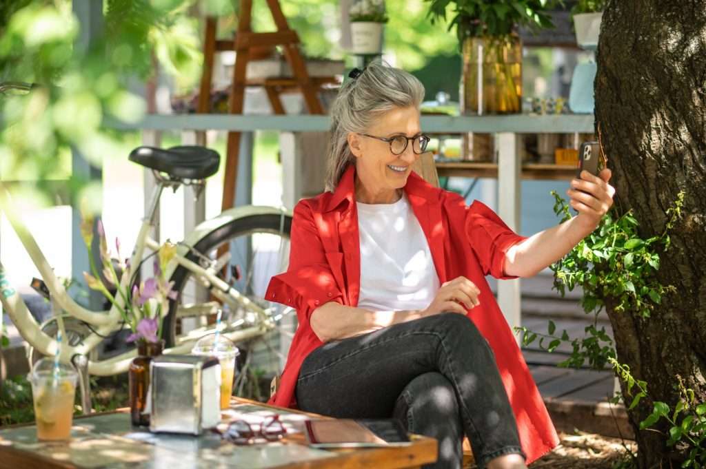 Smiling older woman on a video call outdoors